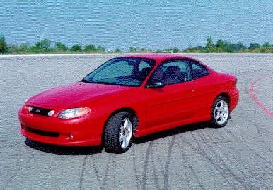 Red SVT Escort prototype from the front three-quarter, with a unique grille and front fascia, alloy wheels and rocker extensions, on a test pad